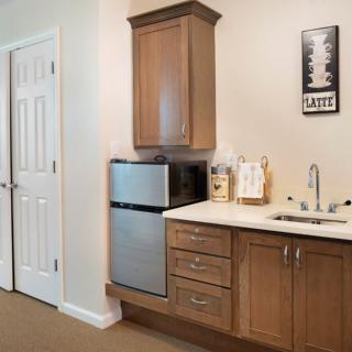 A compact kitchenette featuring a mini fridge, microwave, and cabinetry with a small sink area.