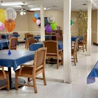 A decorated indoor space with balloons, tables, and chairs set up for a party.