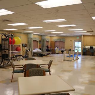 An interior view of a spacious rehabilitation therapy room equipped with exercise gear and bright lighting.