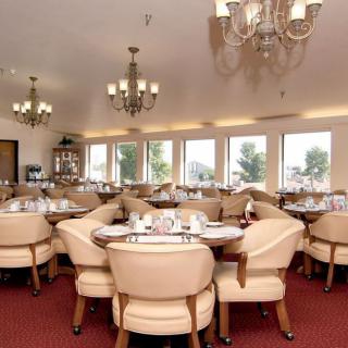 A spacious restaurant dining area with elegant chandeliers and neatly arranged tables.