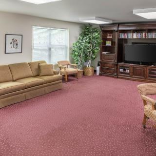 A cozy living room with a sofa, chairs, a large bookshelf, and a television.