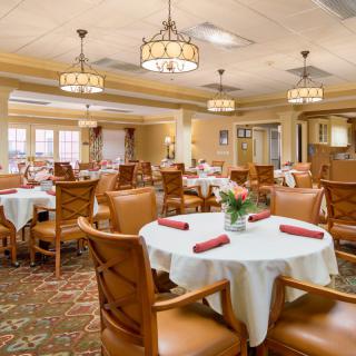 An elegant dining room with neatly arranged tables and chairs, featuring warm lighting and decor.
