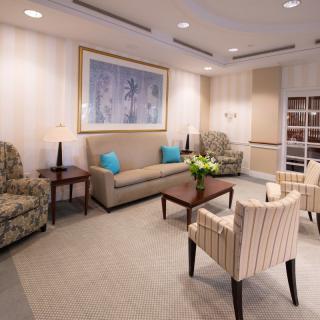 A cozy living room with sofas, chairs and a coffee table, featuring elegant decor and wall artwork.