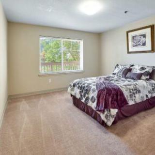 A cozy bedroom featuring a bed with patterned bedding and a window offering natural light.