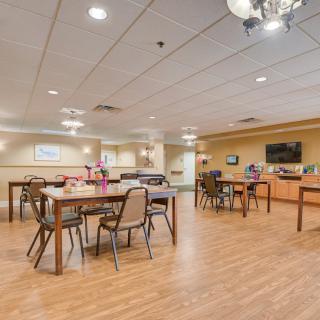A spacious dining area with tables and chairs, featuring a television on the wall and decorative lighting.