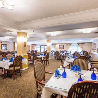Elegant dining area with neatly arranged tables and chairs, featuring blue glassware.