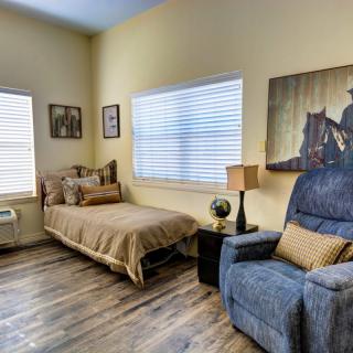 Cozy bedroom with a single bed, recliner chair, and decorative artwork on the walls.