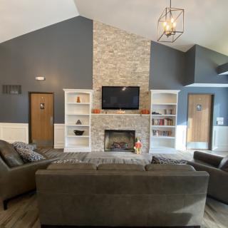 A modern living room featuring a central fireplace with flanking bookshelves, comfortable sofas, and a television mounted above the mantel.