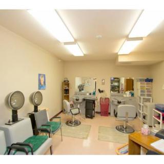 A cozy hair salon with seating, mirrors, and hair dryer stations.