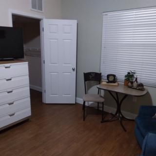 A cozy room with a dresser, TV, small table, and chairs.