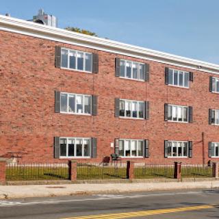 A brick apartment building showcasing a series of windows and a clean exterior.
