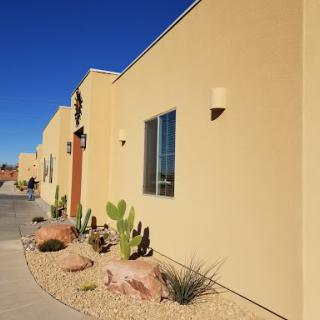 A brightly colored building with desert landscaping and clear blue skies.
