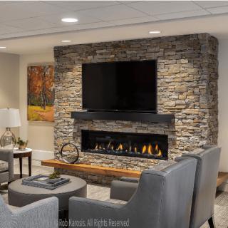 A modern living room features a stone fireplace with a mounted television and cozy seating.