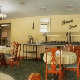 An empty restaurant dining area with round tables and a buffet setup.