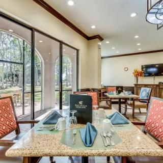 A well-lit restaurant dining area with neatly arranged tables and chairs, featuring large glass doors that open to an outdoor view.