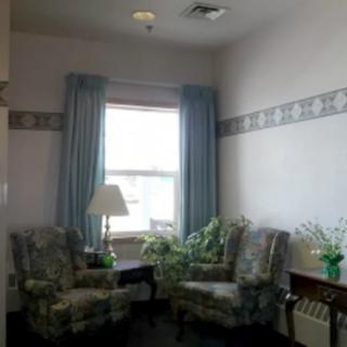 A cozy sitting area with two chairs and a lamp by the window.