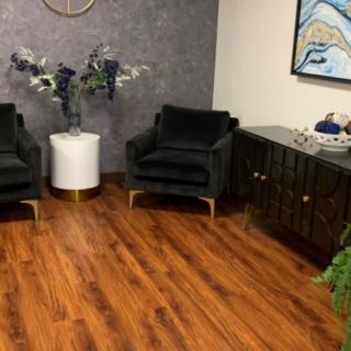 A modern office waiting area with black chairs, a white side table with floral decorations, and a dark cabinet on a hardwood floor.