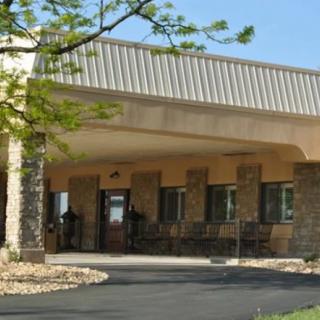 The image shows the entrance of a building with a covered walkway and surrounding trees.