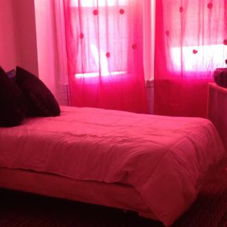 A cozy bedroom with pink curtains and bedding.