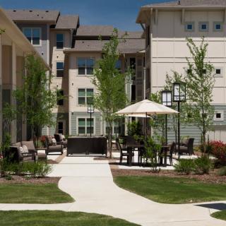 Modern apartment complex with landscaped courtyard and outdoor seating.