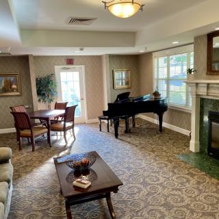 A cozy living room featuring a grand piano, comfortable seating, and a fireplace.
