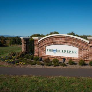 A brick sign welcoming visitors to Culpeper set against a clear blue sky.