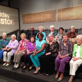 A group of seniors gathered in a studio setting, seated in rows.