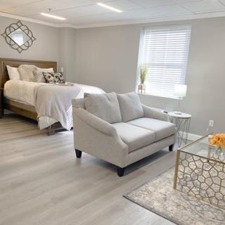 A modern and minimalist bedroom with an integrated living area, featuring a comfortable bed, a stylish sofa, and a decorative coffee table.