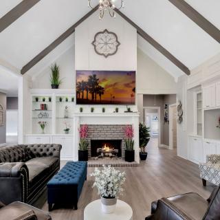 A modern living room with a vaulted ceiling, featuring a fireplace, stylish furniture, and decorative elements.