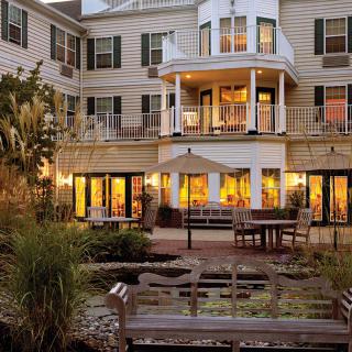 An elegantly designed hotel with glowing windows, surrounded by a peaceful garden setting in the evening.