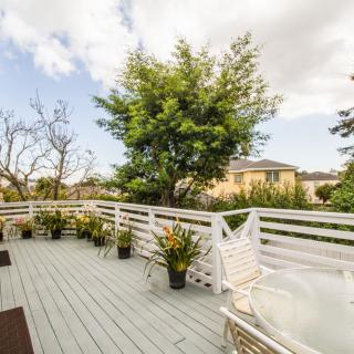 A spacious outdoor deck with potted plants and a view of trees in the background.
