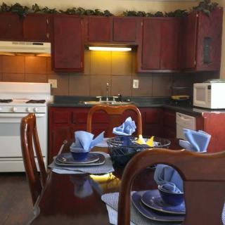 A cozy kitchen with a well-set dining table using blue napkins and matching plates.