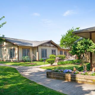 A serene outdoor landscape featuring buildings surrounded by lush greenery and a well-maintained garden.