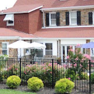 A charming house with a well-kept garden featuring colorful flowers and outdoor seating.