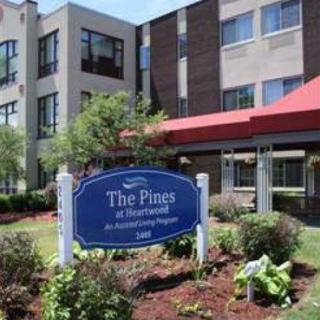 A residential building with a landscaped entrance and a sign reading 'The Pines at Narragansett'.