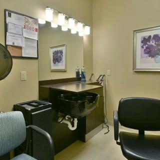 A cozy hair salon interior featuring a mirror, chairs, and wash station with warm lighting.