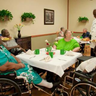 Elderly residents enjoying a meal together in a nursing home's dining area.