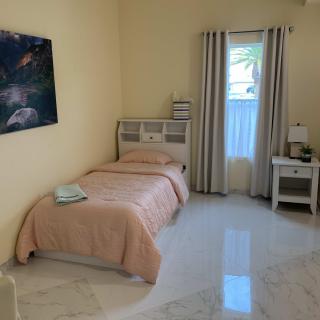 A minimalist bedroom featuring a single bed, nightstand, and a painting on the wall.