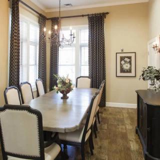 Elegant dining room with a long table, surrounded by chairs and illuminated by a chandelier.