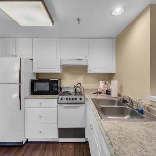A modern kitchen with white cabinets, a refrigerator, stove, microwave, and dual sinks.