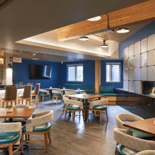 A modern dining area featuring wooden accents and blue walls, with tables and chairs arranged for guests.