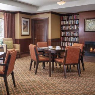 A cozy library room with a fireplace, bookshelves, and seating area.
