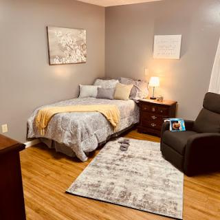 A cozy and inviting bedroom featuring a neatly made bed, a comfortable chair, and tasteful decor.