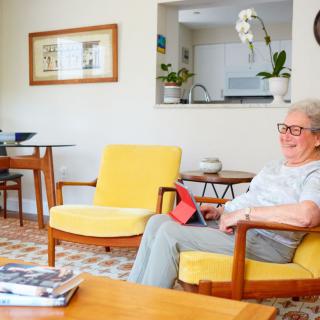 A woman sits comfortably in a modern living room with yellow chairs, enjoying her time.