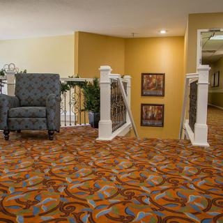 A cozy hallway with patterned carpet, seating, and decorative elements.
