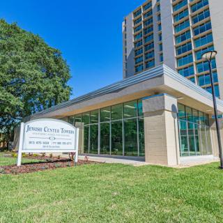 A modern building featuring large glass windows and a welcoming entrance, surrounded by lush green grass.