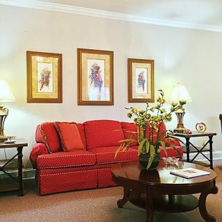 A cozy living room featuring a red sofa, coffee table, and decorative wall art.