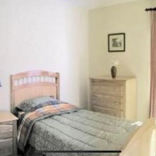A minimalist bedroom featuring a single bed, dresser, and simple decor.