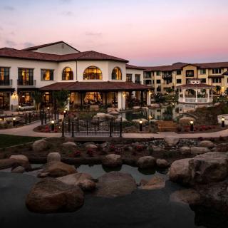 A luxurious resort at sunset with a serene pond in the foreground.