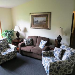 Cozy living room with a sofa, two patterned armchairs, and decorative elements.